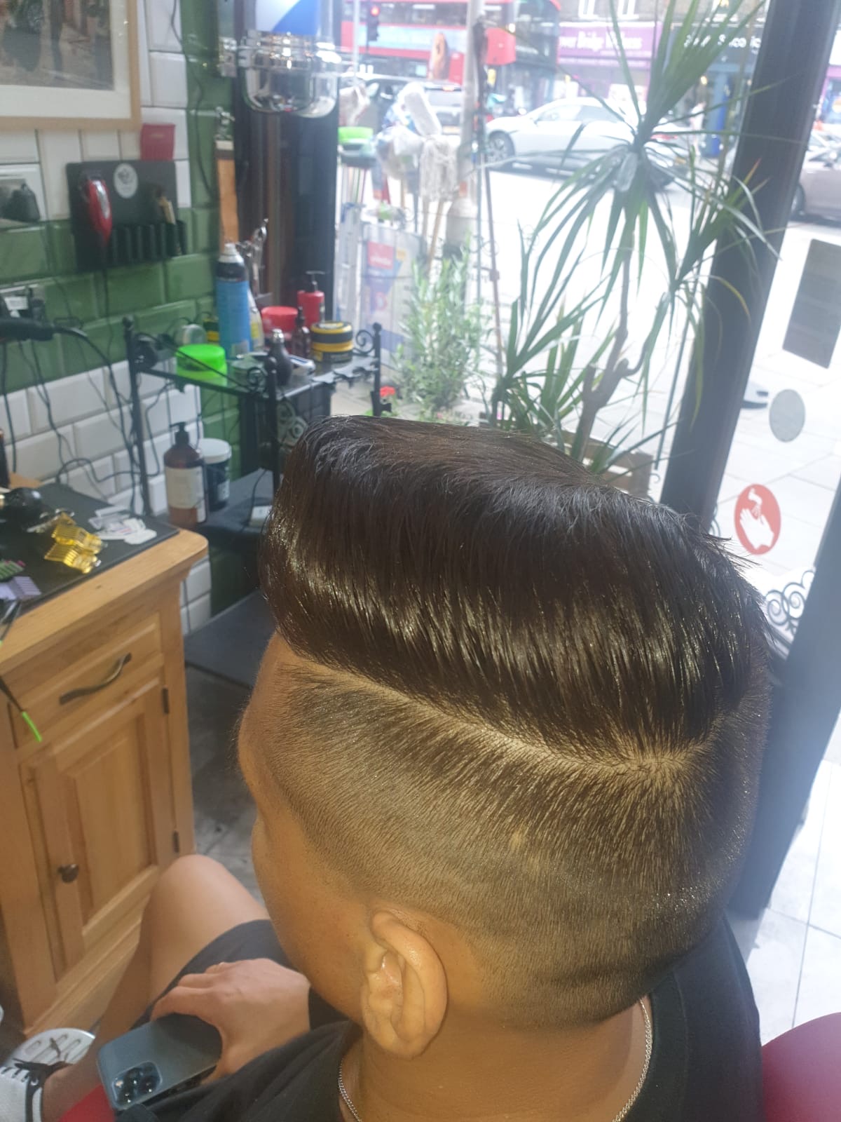 Clippers finishing a sharp side-part skin fade, seen from above