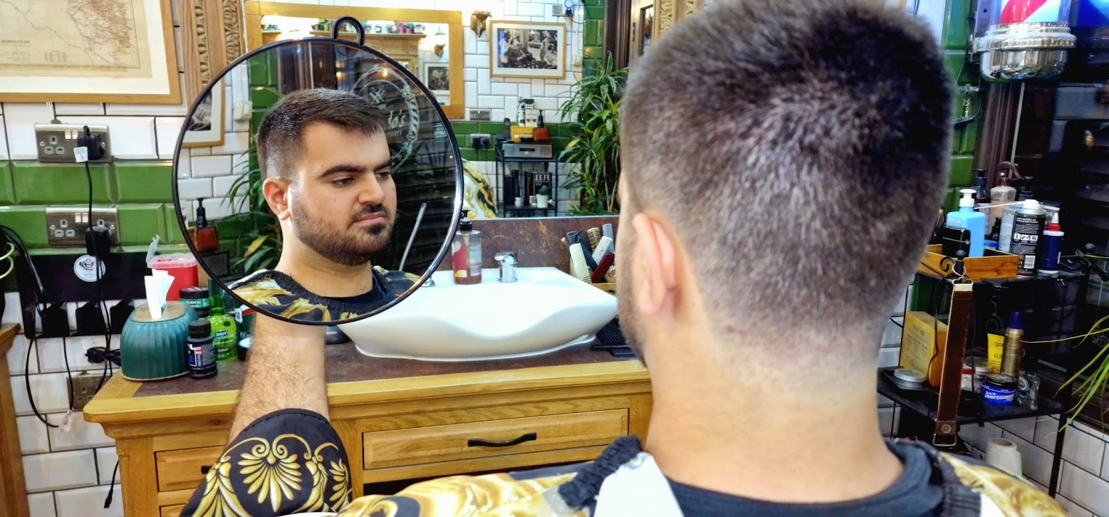 A freshly cut head checked in the round hand mirror against the green tiled wall