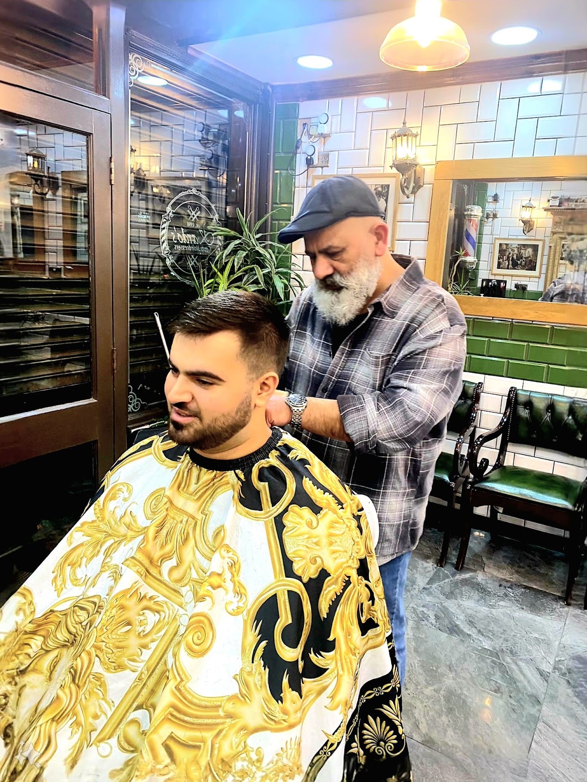 The barber mid-cut behind a client in a gold gown, the full shop interior behind them