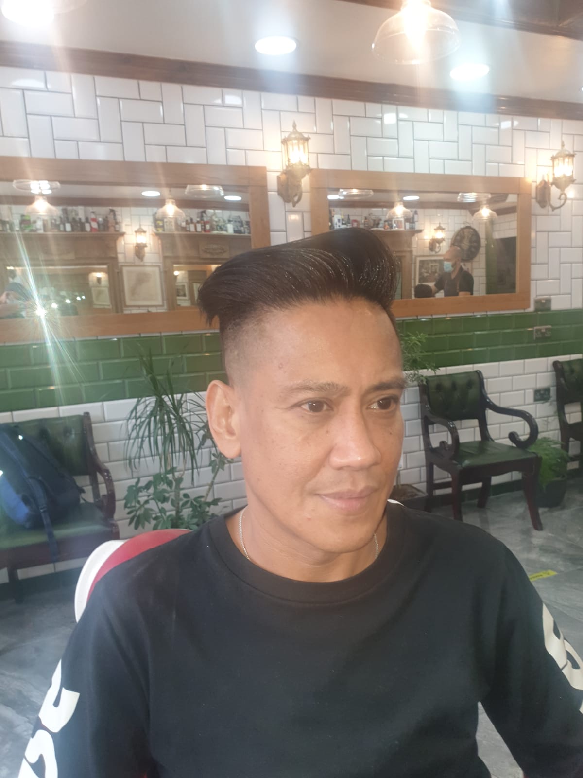 A client in the shop with a finished short back and sides and textured top